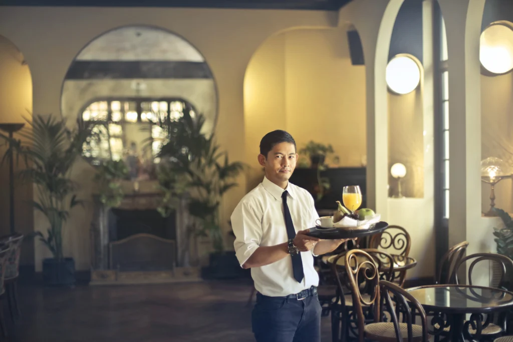 Seorang waiter mengantarkan pesanan minuman sesuai SOP